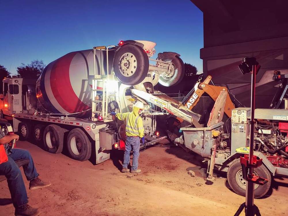 Ready-mix concrete truck feeding a line pump at dusk